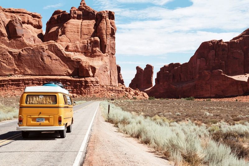 Van Volkswagen jaune sur une route désertique entourée de formations rocheuses rouges aux États-Unis