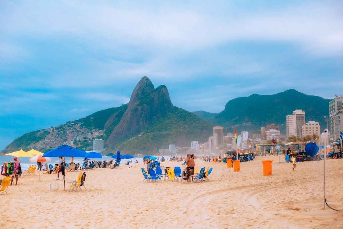 Baigneurs et parasols sur la plage d’Ipanema avec montagnes en arrière-plan