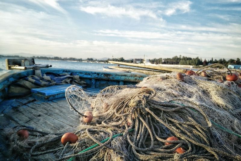 Bateau de pêche en bois avec filets et bouées oranges amassés sur le pont, au port en Tunisie