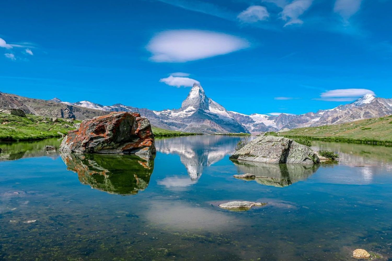 Le Cervin se reflète dans les eaux calmes du lac Stellisee, entouré de rochers, en Suisse
