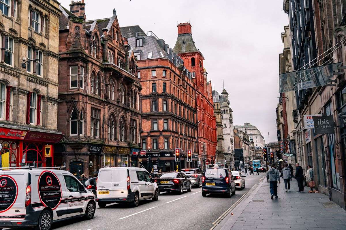 Rue animée bordée d'immeubles historiques avec voitures et piétons