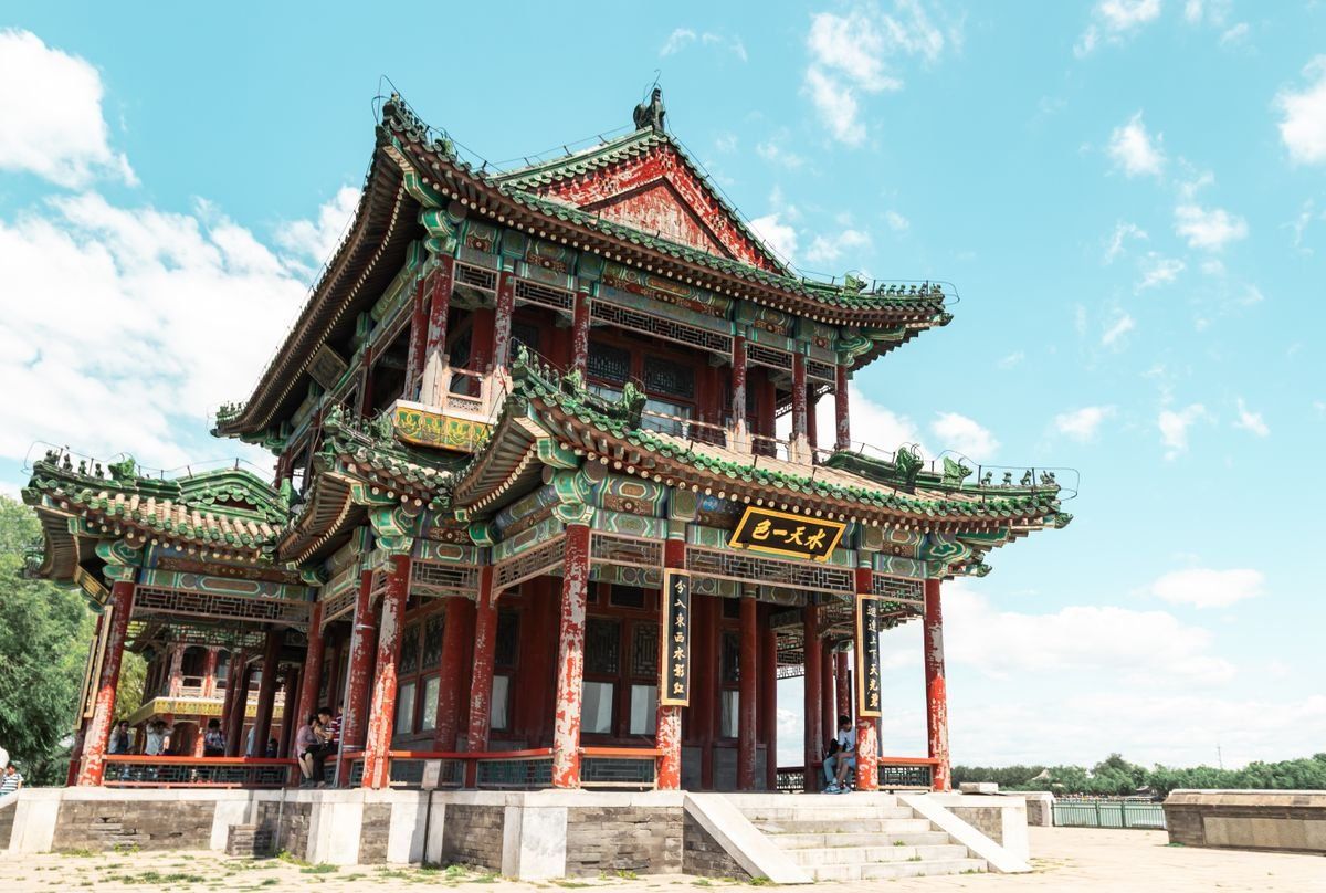 Temple chinois traditionnel aux colonnes rouges et toits ornés sous un ciel bleu