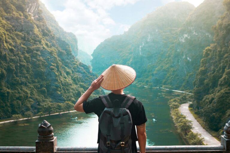 Voyageur de dos avec un chapeau conique vietnamien admirant la vallée karstique de Trang An, au Vietnam