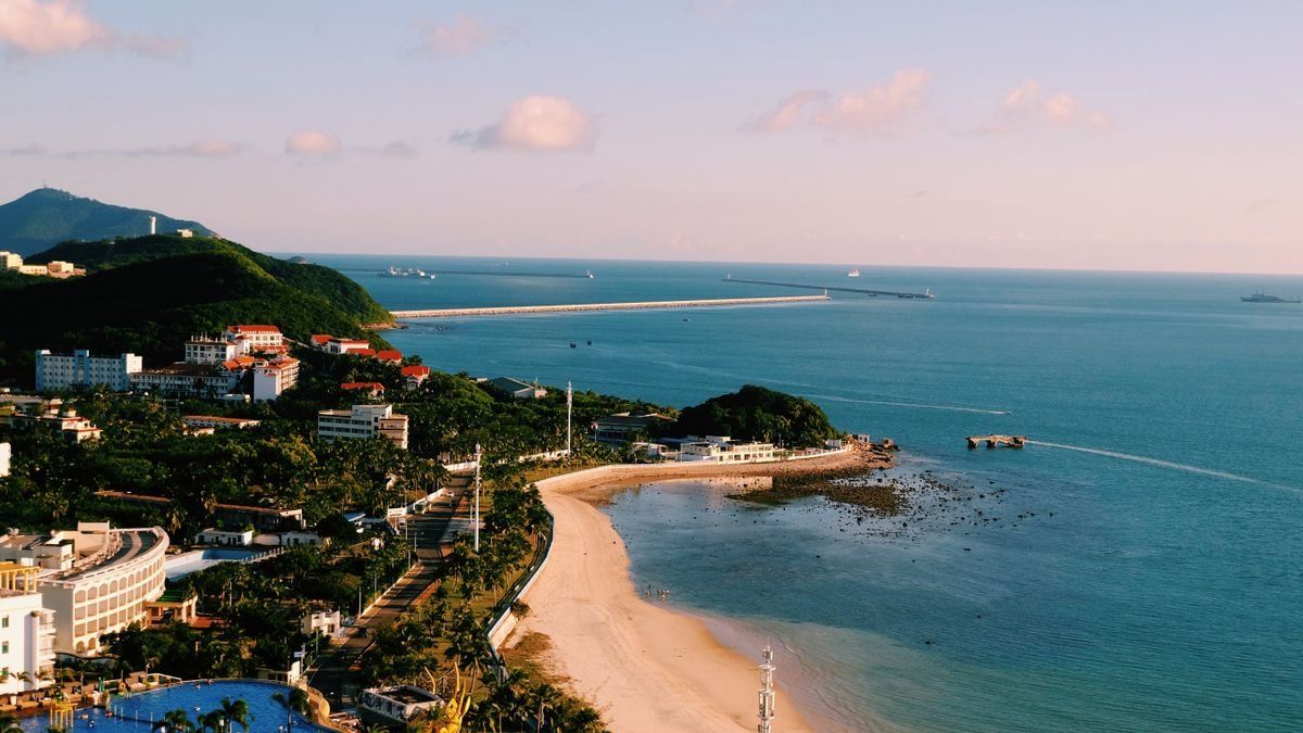 Vue aérienne d’une baie avec plage de sable, hôtels côtiers et mer calme