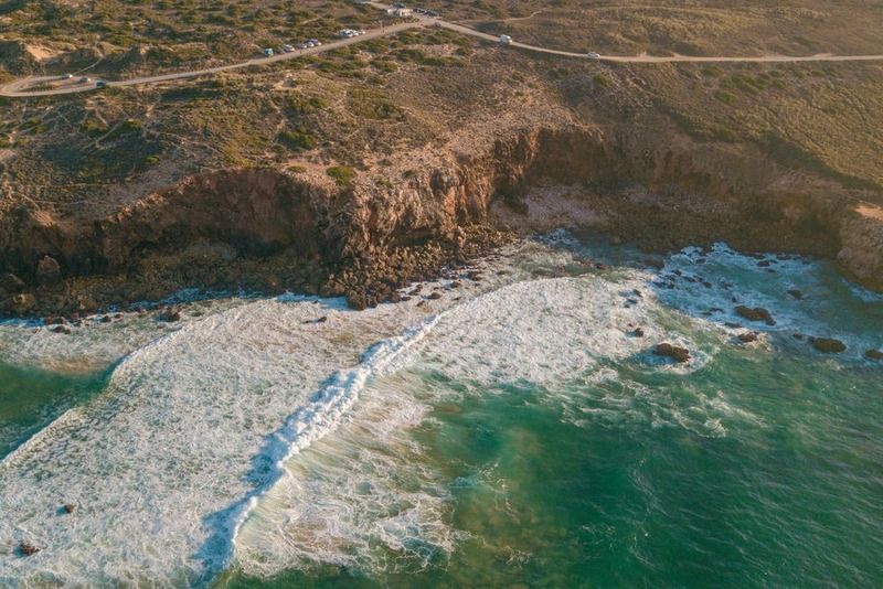 Vue aérienne des falaises et des vagues déferlantes de la plage d'Odeceixe, sur la côte ouest du Portugal