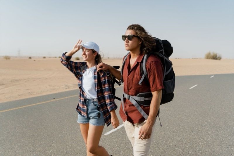 Couple avec sacs a dos sur une route desertique