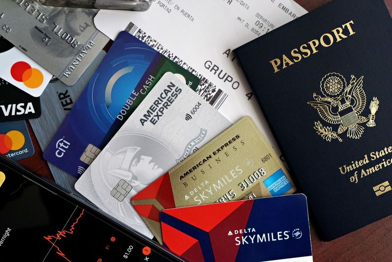Une composition avec un passeport américain, une carte d'embarquement et plusieurs cartes de crédit près d'un téléphone affichant un graphique boursier