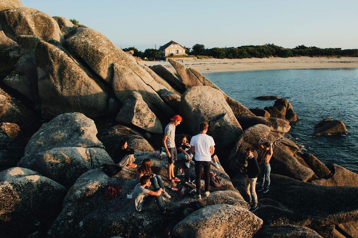 Groupe de jeunes sur de gros rochers au bord de la mer par temps ensoleillé