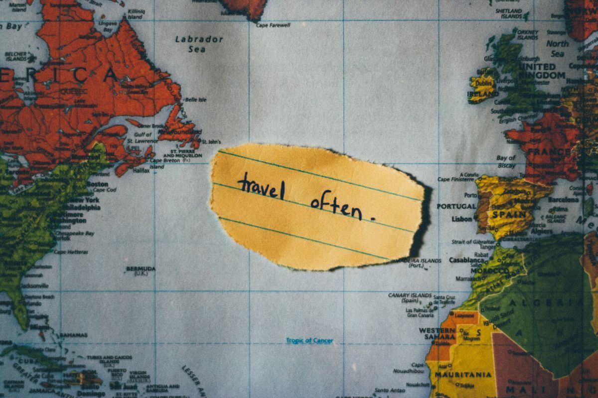 Petit papier jaune avec les mots travel often posé sur une carte du monde