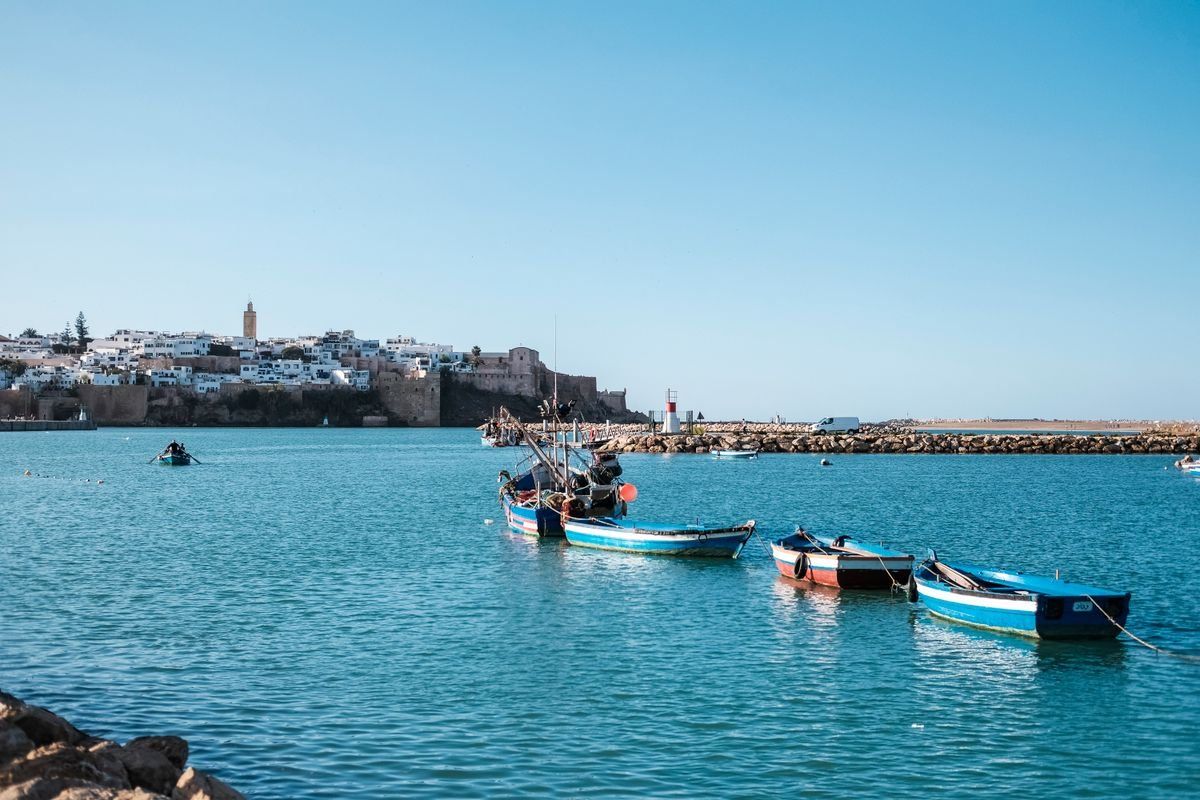 Barques colorées sur une eau calme avec la ville fortifiée de Rabat au loin
