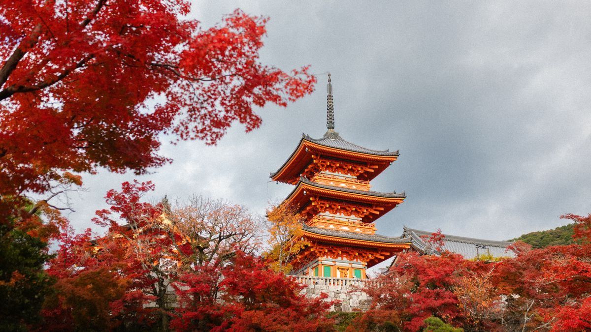 Pagode de Kiyomizu-dera entourée d’érables rouges sous un ciel nuageux