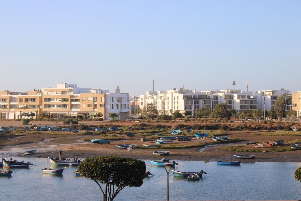 Petits bateaux de pêche amarrés sur l’eau devant des immeubles modernes à Rabat