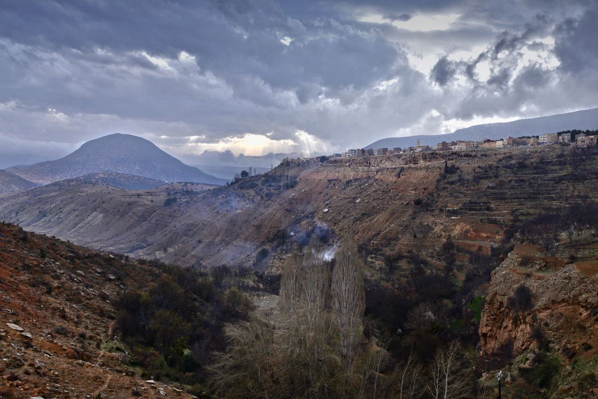 Village perché sur un versant montagneux sous un ciel chargé de nuages