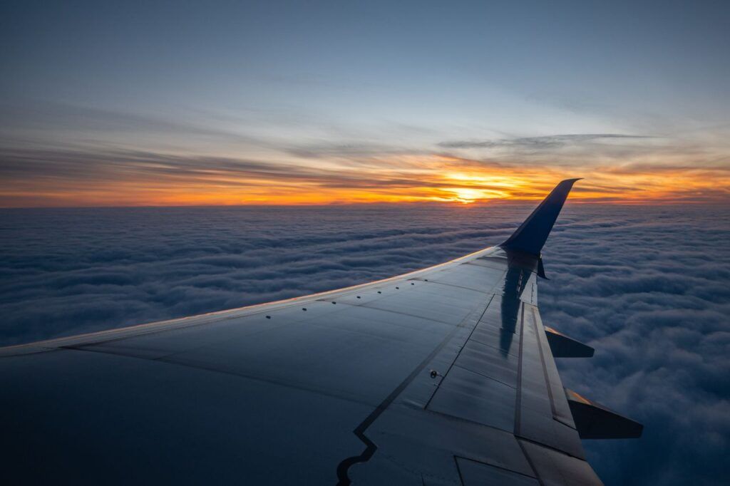 Aile d'avion au-dessus des nuages au coucher du soleil