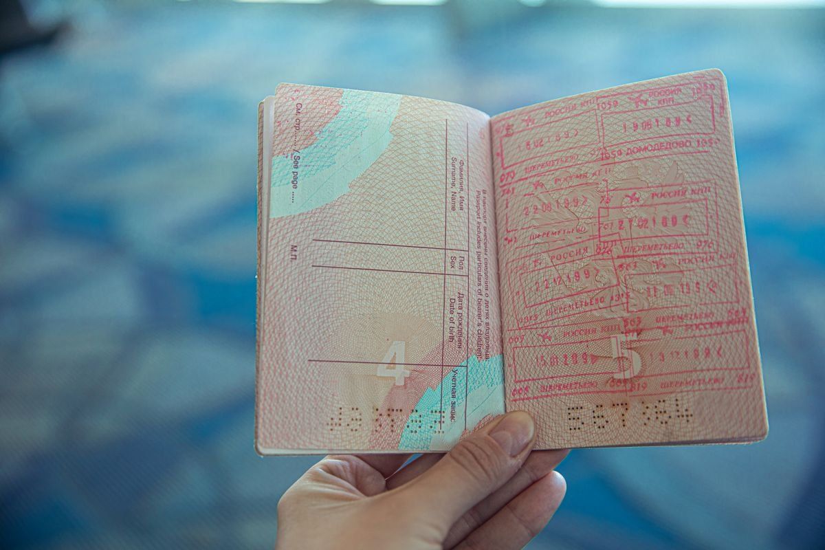 Main tenant un passeport ouvert avec plusieurs tampons d’entrée et de sortie