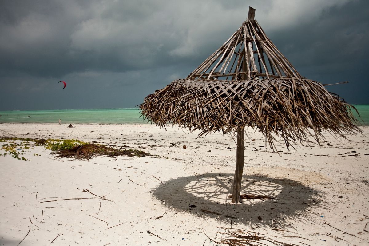 Parasol en bois abîmé sur la plage sous un ciel orageux