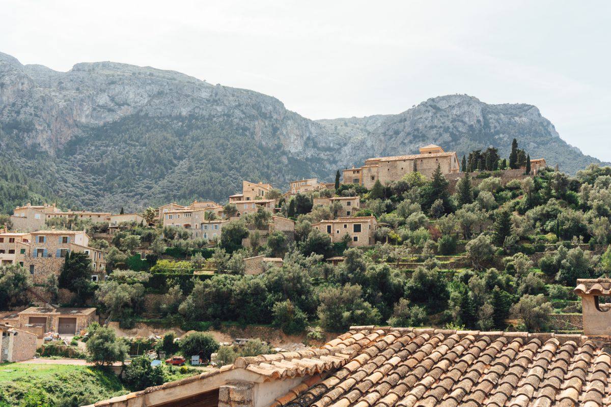 Village de pierre à flanc de colline entouré de verdure et de montagnes